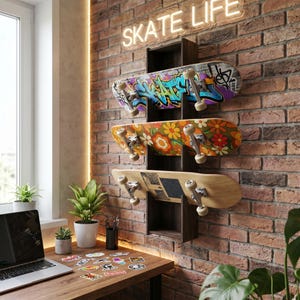 Op de afbeelding: Een donkerbruin houten wandrek met drie skateboards. Het bovenste board heeft kleurrijke graffitikunst, het middelste board heeft een retro oranje en geel bloemenpatroon en het onderste board is van naturel hout met een zwart gripvlak.