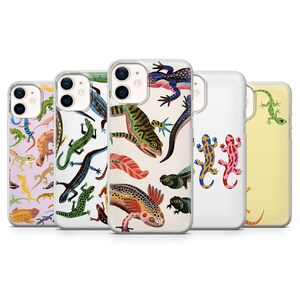 Op de afbeelding: Vijf doorzichtige telefoonhoesjes met diverse illustraties van hagedissen en salamanders. De ontwerpen bevatten kleurrijke patronen van groene, blauwe, oranje en gele reptielen op lichtpaarse, witte en lichtgele achtergronden met dubbele camera-uitsparingen.