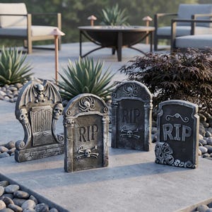 May include: A set of four grey stone-look tombstones featuring various relief carvings including skulls, bats, spiders, and the text RIP. Each tombstone has a weathered texture and distinct decorative elements, arranged on a flat stone surface.