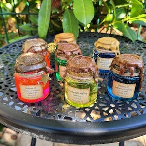 Pode incluir: Uma coleção de seis pequenas garrafas de vidro preenchidas com líquidos vibrantes em vermelho, verde, amarelo e azul. Cada garrafa apresenta uma rolha selada com cera castanha, cordel e uma etiqueta de papel com texto, incluindo Potion of Healing.