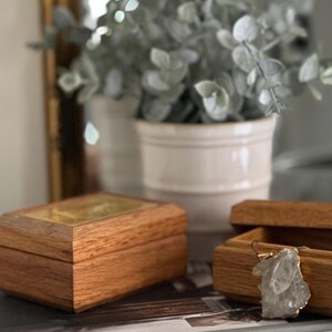 May include: Two wooden boxes with lids open. One box contains a clear crystal pendant with a gold chain. The other box has a gold-coloured interior.