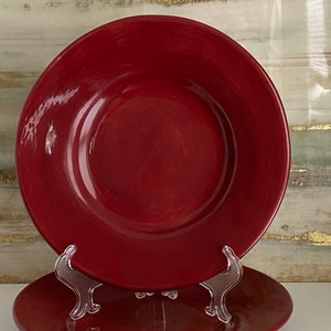 Op de afbeelding: Twee rode keramische borden die op elkaar gestapeld zijn. De borden zijn rond en hebben een glanzende afwerking.