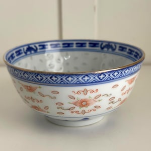 Può includere: Ciotola in porcellana bianca con bordo geometrico blu e finiture dorate. La ciotola presenta un delicato motivo floreale in rosso e verde. Il bordo ha un motivo ripetuto di elefanti blu.