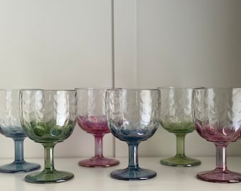 Könnte beinhalten: Satz von sechs klaren Glaskelchen mit einem strukturierten, blasenförmigen Design. Die Kelche haben einen Farbverlauf von Grün, Blau und Rosa.