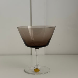 May include: A clear glass stemmed goblet with a brown tinted bowl. The goblet has a gold sticker on the bottom with the text "Made in Czechoslovakia".