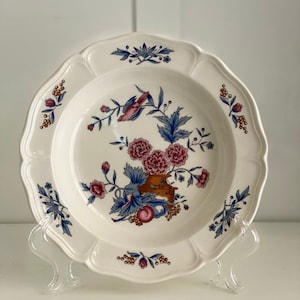 以下が含まれることがあります： 青、ピンク、茶色の花柄が施された白いセラミック製のスープボウルです。ボウルは波打つ縁取りが施され、鳥、花、果物を描いた花柄のモチーフで飾られています。