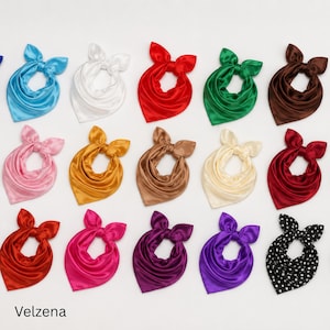 Peut inclure: Une collection de quinze foulards en satin disposés en grille, présentant diverses couleurs unies dont bleu, blanc, rouge, vert, marron, rose, doré, beige, crème, bordeaux, magenta, violet, et un foulard noir à pois blancs. Chaque foulard est noué.