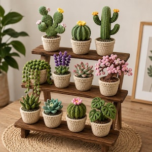 Peut inclure: Une collection de onze plantes crochetées dans de petits pots beiges, disposées sur un support en bois à trois niveaux. Les plantes incluent divers cactus, un collier de perles, de la lavande, une succulente, un arbre à fleurs roses et un monstera.
