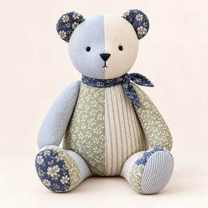 Peut inclure: Un ours en peluche fabriqu&eacute; &agrave; partir de panneaux de tissu en patchwork. L'ours pr&eacute;sente un m&eacute;lange de textiles &agrave; rayures bleu clair, cr&egrave;me, &agrave; motifs floraux vert sauge et bleu fonc&eacute;. Il porte un foulard assorti en tissu floral bleu fonc&eacute;.