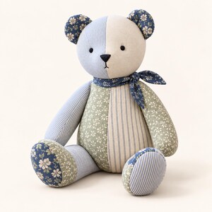 Peut inclure: Un ours en peluche fabriqu&eacute; &agrave; partir de divers morceaux de tissu dans des tons de bleu, vert et cr&egrave;me. L'ours pr&eacute;sente une t&ecirc;te bicolore, des motifs floraux et ray&eacute;s, un foulard bleu fonc&eacute; au cou, ainsi que de petits yeux noirs et un nez brod&eacute;.