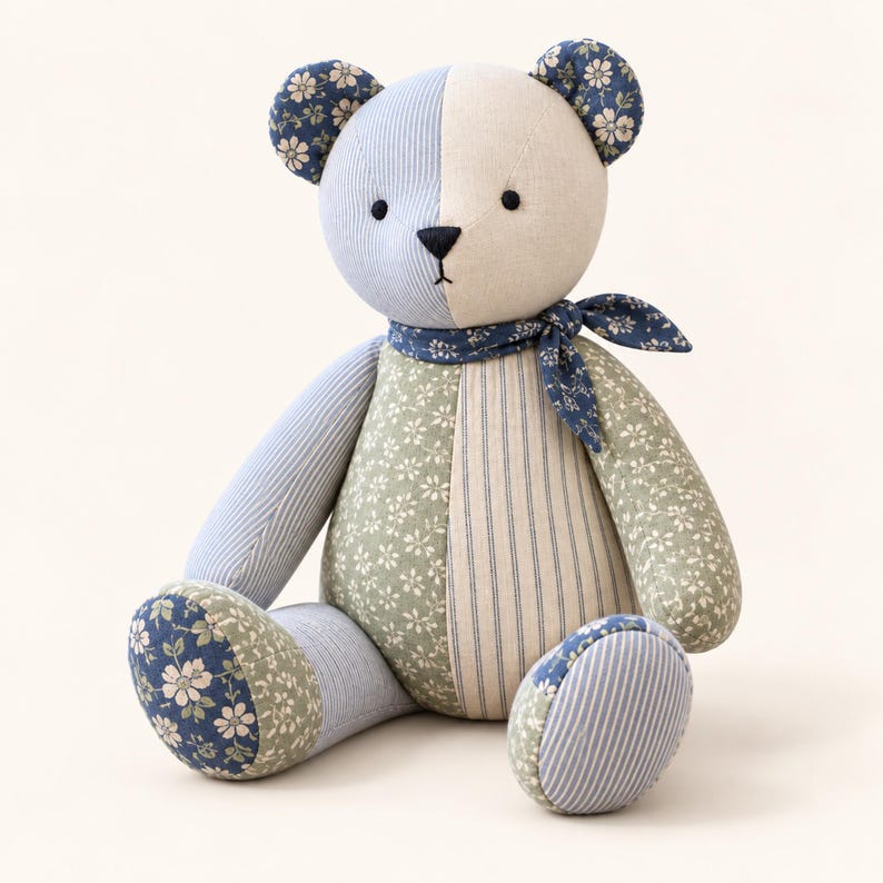 Peut inclure: Un ours en peluche fabriqu&eacute; &agrave; partir de divers morceaux de tissu dans des tons de bleu, vert et cr&egrave;me. L'ours pr&eacute;sente une t&ecirc;te bicolore, des motifs floraux et ray&eacute;s, un foulard bleu fonc&eacute; au cou, ainsi que de petits yeux noirs et un nez brod&eacute;.