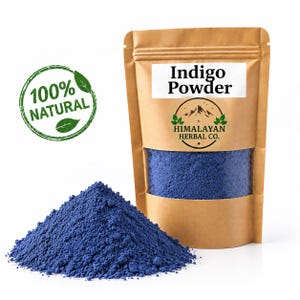 Peut inclure: Un sachet en papier brun contenant de la poudre d'indigo bleu foncé avec une fenêtre transparente, étiqueté Indigo Powder et Himalayan Herbal Co. Un tampon vert circulaire à gauche indique 100% NATURAL. Un tas de poudre bleue est devant.