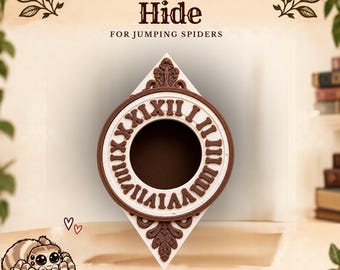 Puede incluir: Un escondite para arañas en forma de diamante con un diseño de esfera de reloj circular, números romanos marrones en relieve sobre fondo blanco y adornos de volutas. El texto dice Gothic Clock Hide for jumping spiders y Made by Spood & Board.