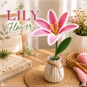 May include: A crocheted pink and white lily flower with yellow stamens and a green stem in a white fluted ceramic vase tied with twine. The text LILY Flower is visible in the upper left corner above a book titled The Kinfolk Tome.