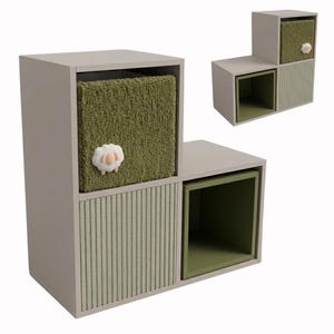 May include: A light gray tiered storage unit featuring three square compartments. One compartment contains a fuzzy olive green fabric bin adorned with a small white sheep figure. Another compartment has a light green ribbed door, and the third is open.