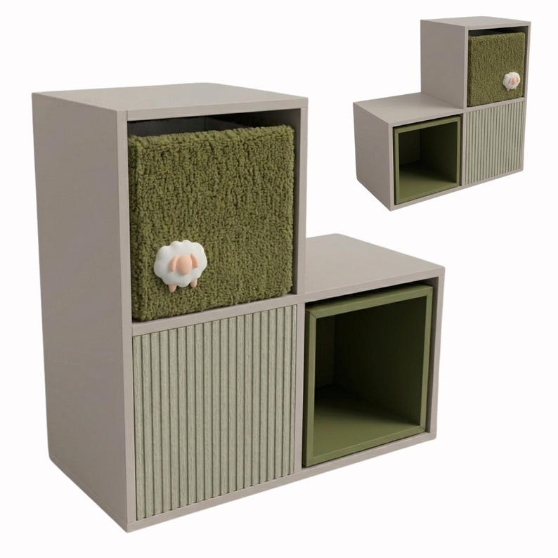 May include: A light gray tiered storage unit featuring three square compartments. One compartment contains a fuzzy olive green fabric bin adorned with a small white sheep figure. Another compartment has a light green ribbed door, and the third is open.