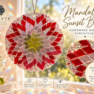 Op de afbeelding: Een ronde mozaïek zonnevanger genaamd Mandala Sunset Bloom van Enlyte Studio, met een geometrisch patroon van rode, roze en gele glastegels geaccentueerd met kleine doorzichtige kralen, opgehangen aan een metalen ketting voor een raam.