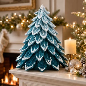 Puede incluir: Un árbol de Navidad decorativo de ganchillo con ramas superpuestas en forma de hoja en tonos azul y verde azulado. Los bordes de cada hoja están detallados con puntadas blancas texturizadas que imitan la apariencia de nieve recién caída.
