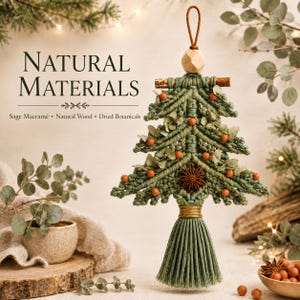 May include: A sage green macramé Christmas tree ornament featuring natural wood beads, dried botanical accents, and small orange berries. The text reads NATURAL MATERIALS, Sage Macramé, Natural Wood, Dried Botanicals. It has a tassel base.