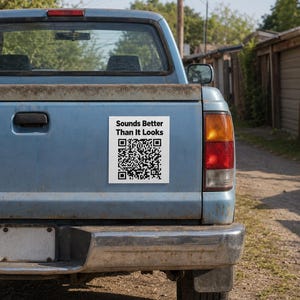 May include: A rectangular white sticker applied to the tailgate of a light blue pickup truck. The sticker features the black text Sounds Better Than It Looks above a black and white QR code. The truck has a metallic bumper and a red taillight.