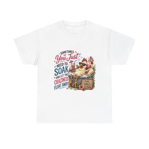 May include: A white t-shirt featuring a graphic of a chicken wearing sunglasses, relaxing in a bathtub with a drink. The text reads: SOMETIMES YOU JUST NEED TO SOAK AND LET THE CRAZINESS FLOAT AWAY! A small sign nearby says: PEACE, BUBBLES, NO DRAMA.