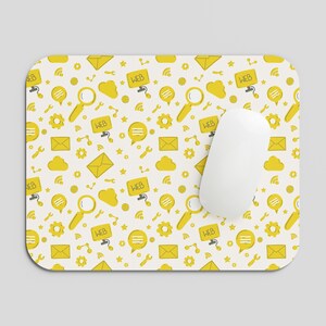 May include: A rectangular mouse pad with a white background featuring a repeating yellow pattern of magnifying glasses, envelopes, gears, cloud shapes, and speech bubbles containing the text WEB. A smooth white computer mouse rests on top.