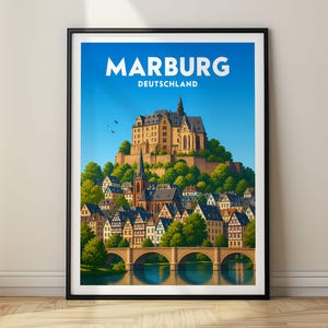 以下が含まれることがあります： ドイツの都市マールブルクを描いた額装されたトラベルポスター。イラストには、丘の上に建つ大きな城、木組みの家々が並ぶ町、石橋、そして2羽の鳥が飛ぶ青い空の下を流れる川が描かれています。上部には「MARBURG DEUTSCHLAND」の文字があります。
