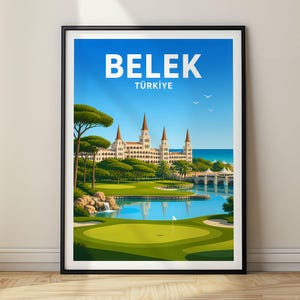 May include: A framed travel poster featuring the text BELEK TÜRKİYE at the top. The illustration depicts a golf course with a green, a small pond, a waterfall, and a large white building with multiple towers near the blue sea under a clear sky.