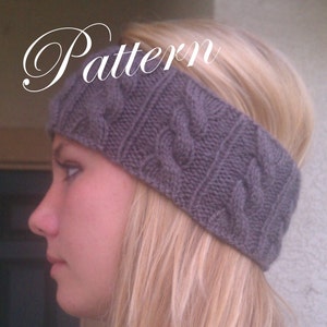 May include: A gray knitted headband with a cable knit pattern. The headband is worn by a person with long blonde hair.