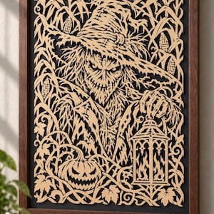 May include: A framed wall art piece featuring a laser-cut wooden design of a scarecrow wearing a wide-brimmed hat, standing in a cornfield. The scarecrow holds a lantern, and a carved jack-o'-lantern sits at the base against a black background.