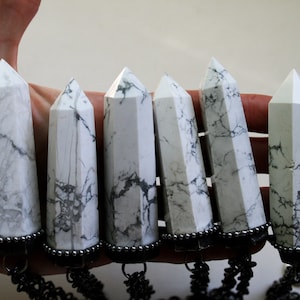 May include: Six white howlite crystal points with black metal accents and chains. The crystals are polished and have a marbled appearance.