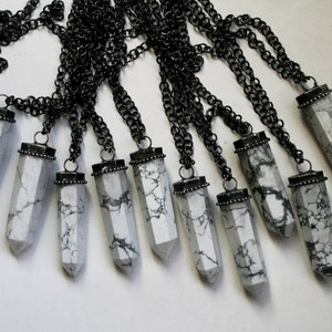 May include: Ten white howlite crystal point pendants on black chains. Each pendant has a silver-toned metal cap.