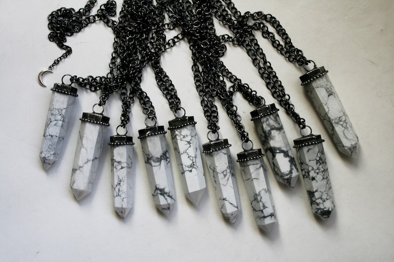 May include: Ten white howlite crystal point pendants on black chains. Each pendant has a silver-toned metal cap.