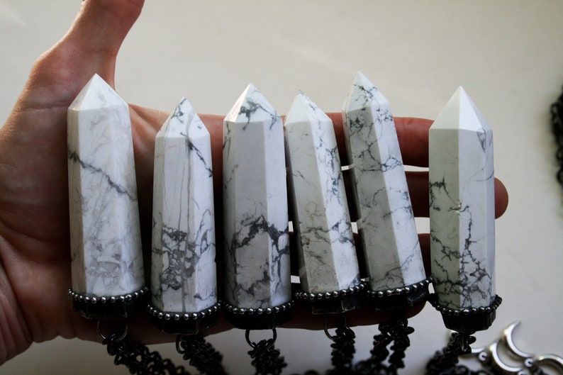 May include: Six white howlite crystal points with black metal accents and chains. The crystals are polished and have a marbled appearance.