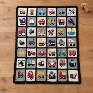 May include: A rectangular crochet blanket featuring a grid of squares, each displaying a different colorful yarn-stitched vehicle or transport motif. The squares are bordered in white and gray, with a thick black crochet border surrounding the entire piece.