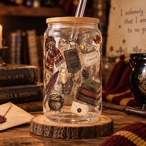 May include: A clear glass tumbler with a bamboo lid and a glass straw, featuring a printed design of a scarf, round glasses, a golden snitch, a Platform 9 3/4 ticket, books, a quill, a candle, a key, a cauldron, and a sealed envelope.