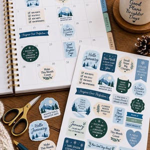 Peut inclure: Une page de calendrier de janvier à spirales et une planche d'autocollants avec des motifs hivernaux et des phrases motivantes comme Hello January, New Month New Goals et Progress Over Perfection, avec des ciseaux dorés et un stylo bleu.