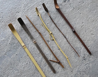 Puede incluir: Un conjunto de seis cucharas de té y agitadores de bambú, largos y delgados, dispuestos en diagonal. El set incluye varios tonos de bambú natural, desde amarillo claro hasta marrón oscuro, con texturas anudadas y detalles de cordón.