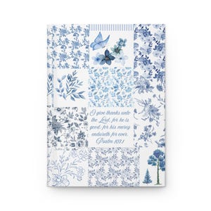 May include: A hardcover journal featuring a blue and white patchwork design with floral patterns, leaves, and a butterfly. The center panel displays the text: I give thanks unto the Lord, for he is good: for his mercy endureth for ever. Psalm 107:1.