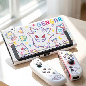 May include: A white gaming console and two detachable controllers featuring a colorful Gengar character print. The design includes various small icons like stars, moons, potions, and books, with the text GENGAR printed in multicolored letters.