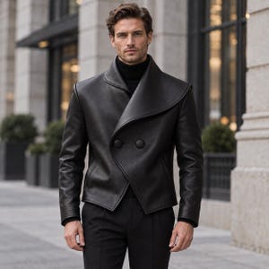 Könnte beinhalten: Eine schwarze Lederjacke mit breitem Schalkragen, langen Ärmeln und einer zweireihigen Vorderseite mit zwei großen, runden, stoffbezogenen Knöpfen. Die Jacke wird über einem schwarzen Rollkragenpullover getragen und mit einer schwarzen Hose kombiniert.