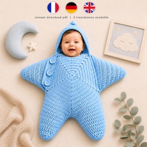 May include: A light blue crocheted baby bunting shaped like a five-pointed star with a hood and three round buttons on the front. The text instant download pdf | 2 translations available is visible at the top of the image.