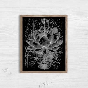 May include: A framed black and white art print featuring a detailed illustration of a lotus flower. The artwork has a geometric design with celestial elements. The print is in a natural wood frame, suitable for home decor.