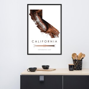 Può includere: Una mappa topografica incorniciata della California con un effetto rilievo tridimensionale in tonalità marroni e bianche. La stampa riporta il testo CALIFORNIA e TOPOGRAPHIC MAP, insieme a una scala altimetrica a colori in metri.