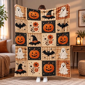May include: A quilted throw blanket featuring a repeating grid pattern of Halloween-themed squares. The design includes orange jack-o'-lanterns, white ghosts, black witch hats, black bats, and orange flowers on black and plaid backgrounds.