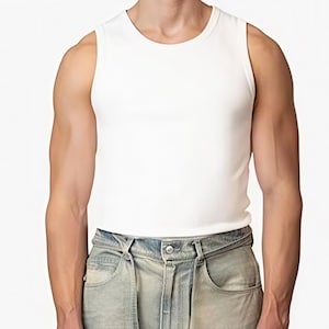 Könnte beinhalten: Ein schlichtes, ärmelloses weißes Tanktop mit Rundhalsausschnitt, kombiniert mit einer hellblauen Jeans aus Denim mit sichtbarem Metallknopf an der Taille und Vordertaschen. Das Kleidungsstück ist vom Oberkörper bis zum Oberschenkel zu sehen.