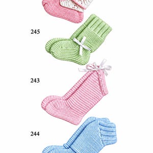 Könnte beinhalten: Vier Paar gestrickte Babyschuhe mit den Nummern 246, 245, 243 und 244. Die Schuhe sind rosa mit weißer Spitzenstulpe, hellgrün mit weißer Schleife, einfarbig rosa mit weißer Schleife und hellblau mit einem gerippten Stulpendesign.