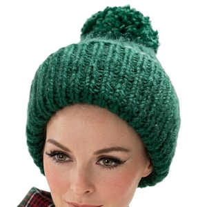Peut inclure: Un bonnet en tricot vert foncé avec une texture côtelée épaisse et un pompon assorti sur le dessus. Le bonnet est associé à une écharpe à carreaux verts et rouges. Le texte "Style No. 1279" est imprimé au bas de l'image.