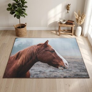 Peut inclure: Un tapis rectangulaire orné d'une impression photographique haute résolution représentant la tête d'un cheval brun de profil. Le cheval présente une liste blanche sur le chanfrein et une crinière sombre, sur un fond flou et brumeux.