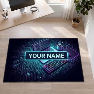 Peut inclure: Un tapis de bureau rectangulaire avec un fond sombre orné de motifs de circuits imprimés bleu néon, un ordinateur portable affichant du code, un clavier et une tasse. Un encart central affiche le texte personnalisable YOUR NAME.